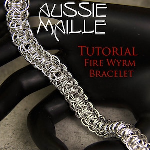 Puede incluir: Una pulsera de cota de malla plateada con un patrón tejido detallado. La pulsera se muestra sobre una superficie negra. El texto de la imagen dice "AUSSIE MAILLE" y "TUTORIAL Fire Wyrm BRACELET."