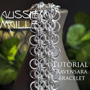 May include: A silver chainmail bracelet with a woven pattern, known as the Ravensara bracelet. The bracelet is on a dark background with green foliage.