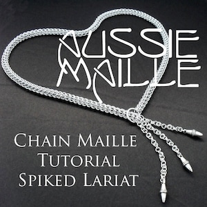 Pode incluir: Um laçador de malha de corrente prateado com três pontas penduradas na extremidade. A malha de corrente tem a forma de um coração e o texto "Aussie Maille Chain Maille Tutorial Spiked Lariat" está impresso abaixo.