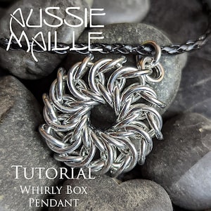 Può includere: Un ciondolo in metallo argentato a forma di scatola rotante, un tipo di gioiello in maglia. Il ciondolo è appeso a un cordino in pelle nera e poggia su un letto di pietre grigie. Il testo "TUTORIAL WHIRLY BOX PENDANT" è visibile sotto il ciondolo.