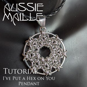 May include: A silver chainmail pendant in the shape of a circle with a smaller circle in the center. The pendant is hanging from a black leather cord. The text "I've Put A Hex On You Pendant" is below the pendant.