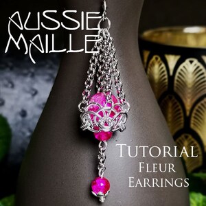 May include: A silver chain earring with a pink glass bead and a silver chain dangle. The earring is hanging from a mannequin's ear. The text "TUTORIAL FLEUR EARRINGS" is visible in the image.