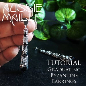 May include: A pair of silver and black graduating Byzantine chainmail earrings. The earrings are long and dangle, with the chainmail gradually getting larger as it goes down. The earrings are made with small black beads.