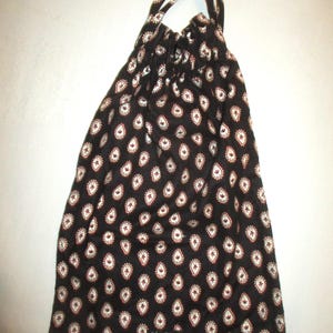 May include: A black drawstring bag with a white and red paisley pattern. The bag has a white label with the text "Vera Bradley" on it.