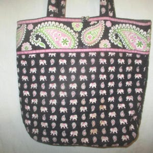 May include: A quilted tote bag featuring a dark brown base with a repeating pattern of small light pink elephants and paisley shapes. The top section displays a larger, horizontal band with a vibrant green and pink paisley floral design.