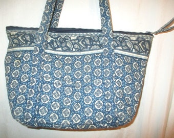 May include: A blue and white patterned tote bag with a zipper closure. The bag has two top handles and a paisley design.