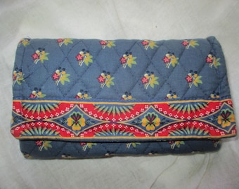 May include: A blue quilted wallet with a red, yellow, and green floral pattern border.