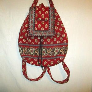 May include: Red and floral patterned backpack with a drawstring closure and adjustable straps.