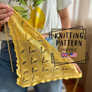 Puede incluir: Un chal triangular tejido en color amarillo brillante con un delicado patrón de encaje, aberturas geométricas repetitivas y un borde festoneado. La imagen incluye el texto KNITTING PATTERN PDF FILE junto a pequeños iconos de banderas británica y estadounidense.