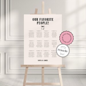 May include: A black and white wedding seating chart with the title "Our Favorite People!" and a list of tables and names. The chart is on a wooden easel.