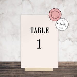 May include: White table number card with black text that reads "TABLE 1". The card is on a wooden surface.