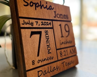 May include: A wooden plaque with the name "Sophia Jones" engraved on it. The plaque also includes the date "July 7, 2024", the weight "7 pounds 8 ounces", the height "19 inches", the time "8:21 AM", and the location "Dallas, Texas".