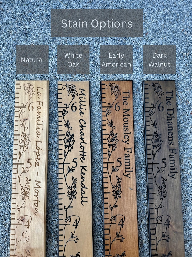 May include: Four wooden growth charts with different stain options labeled Natural, White Oak, Early American, and Dark Walnut. Each board features engraved floral vines, measurement markings from 4 to 6 feet, and personalized family names.