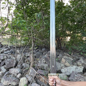 May include: A silver sword with a gold hilt and red gems. The sword has a long, straight blade and a pointed tip. The hilt is decorated with intricate designs.