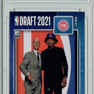 May include: A graded rookie card featuring Cade Cunningham of the Detroit Pistons. The card is from the 2021-22 Panini Instant series, with a limited print run and a Gem Mint 10 grade. The card has the text "DRAFT 2021".