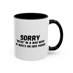 May include: White coffee mug with a black rim and handle. The mug has black text that reads "Sorry "We're" in a bad mood my wife's on her period."