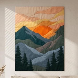 May include: A fabric wall hanging featuring a layered landscape of stitched mountains in shades of blue, gray, and green, topped with a sunset sky in gradients of orange, yellow, and peach, with dark green pine tree silhouettes at the base.