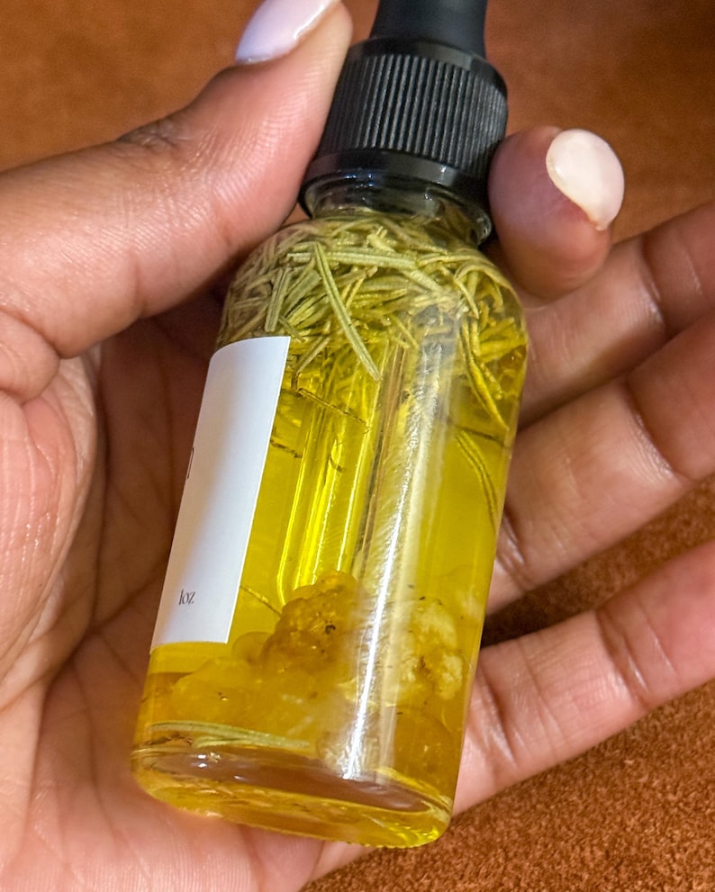 Puede incluir: Una botella de vidrio transparente con un gotero negro en la parte superior llena de un l&iacute;quido amarillo y hierbas verdes. La botella est&aacute; etiquetada con "1oz".