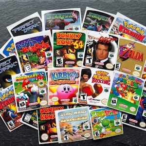 Peut inclure: Une collection d'étiquettes rectangulaires pour cartouches de jeux vidéo Nintendo 64 présentant des illustrations colorées et des titres tels que Super Mario 64, Mario Kart 64, Donkey Kong 64, Star Fox 64, Kirby 64, GoldenEye 007, Zelda et Banjo-Kazooie.