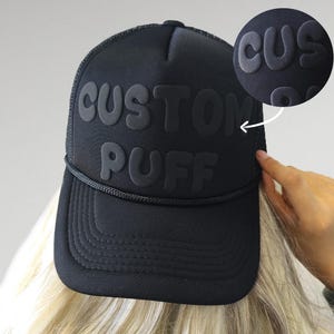 Puede incluir: Gorra de camionero negra con las palabras "CUSTOM PUFF" en letras en relieve y esponjosas.