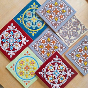 May include: Set of eight decorative ceramic tiles with intricate geometric patterns in shades of red, blue, green, yellow, orange, and grey.