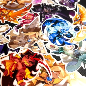 May include: A collection of colorful cartoon character stickers featuring various designs, including a witch, a dragon, a ghost, and a gingerbread cookie. The stickers are printed on white paper and have a glossy finish.