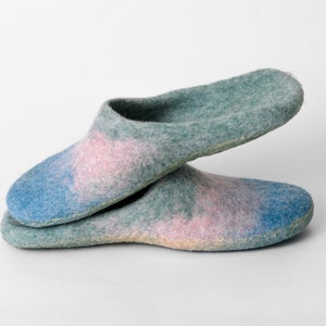 May include: A pair of felted wool slippers in shades of blue, pink, and green. The slippers have a soft, textured appearance and a slip-on design, ideal for indoor wear. The color palette creates a watercolor effect.