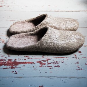 May include: A pair of gray wool slippers on a weathered wooden surface.