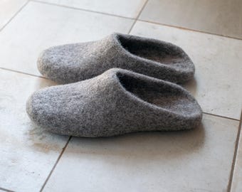May include: A pair of gray felt slippers. The slippers are a muted gray color and have a simple, rounded design. They are made of a soft, textured material and appear comfortable for indoor wear.