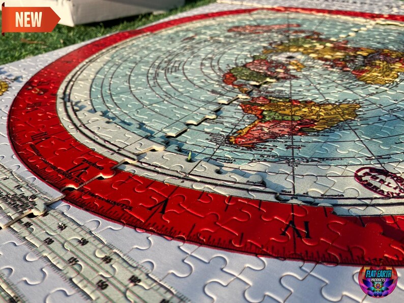May include: A flat earth jigsaw puzzle with a red border and a map of the world. The puzzle is partially assembled and shows the continents of North America, South America, Europe, Africa, and Asia. The puzzle is made by Flat Earth Products.