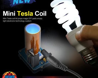May include: A small Tesla coil kit with a blue light glowing from the top. The kit is connected to a power adapter and is shown lighting up a fluorescent light bulb. The text "NEW Mini Tesla Coil" is displayed at the top of the image.