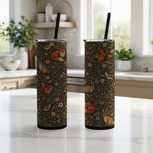 Può includere: Due bicchieri isolati in acciaio inossidabile con cannucce nere. I bicchieri presentano un motivo verde scuro con animali del bosco, tra cui volpi, scoiattoli e conigli, insieme a fiori e foglie.