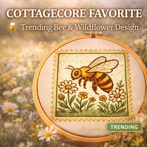 May include: A cross-stitch embroidery hoop featuring a bee and wildflower design. The text "COTTAGECORE FAVORITE" and "Trending Bee & Wildflower Design" are displayed at the top. The word "TRENDING" is at the bottom. The design is set against a blurred floral background.