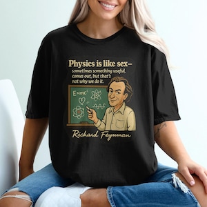 May include: Black t-shirt featuring a cartoon of Richard Feynman next to a chalkboard with the equation E=mc². The shirt includes the quote "Physics is like sex..." and the name "Richard Feynman".
