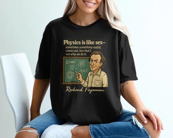 Könnte beinhalten: Schwarzes T-Shirt mit einer Karikatur von Richard Feynman und dem Zitat "Physik ist wie Sex..." sowie der Gleichung E=mc². Der Name "Richard Feynman" ist ebenfalls abgebildet.