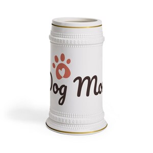 May include: White ceramic dog bone shaped umbrella stand with gold trim and the text "Dog Mom" in black lettering with a pink paw print and heart.