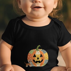 Puede incluir: Body de bebé negro con un diseño de calabaza de retazos coloridos con una cara de linterna. Un perro pequeño está al lado de la calabaza. El body es de manga corta y adecuado para Halloween.
