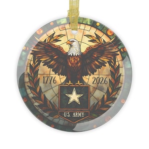 May include: A round ornament featuring a stained-glass design with a bald eagle with outstretched wings. The ornament includes the text "1776" and "2026", and the words "U.S. ARMY" below a star emblem. A gold ribbon is attached for hanging.