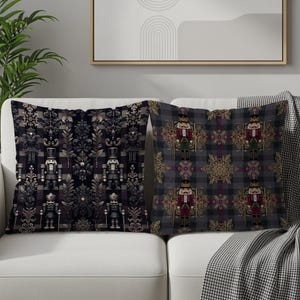 May include: Two decorative throw pillows with holiday-themed designs. One pillow features a repeating pattern of nutcrackers and ornate floral elements in dark gray and black. The other pillow has a plaid pattern with nutcrackers in red, green, and gold.
