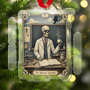 May include: Ornament featuring a skeleton biology teacher with a cup of coffee, wearing a lab coat and glasses. The background includes a chalkboard, a microscope, and the text "THE BIOLOGY TEACHER". The ornament is trimmed with floral designs.