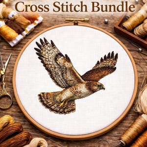 May include: A cross-stitch embroidery hoop featuring a detailed hawk design with brown and tan feathers. The text "Hawk Cross Stitch Bundle" is at the top. The image is surrounded by spools of thread and embroidery supplies.