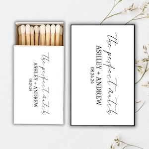 Peut inclure: Deux boîtes d'allumettes blanches avec du texte noir. Le texte indique "the perfect match" et "Ashley + Andrew 08.24.24".