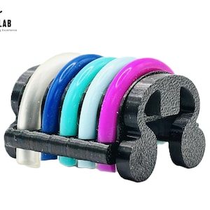 以下が含まれることがあります： 透明、白、青、ターコイズ、水色、ピンクの6つのアーチ型半円リングを備えた、多色3Dプリントオブジェクト。 リングは黒色のテクスチャベースでまとめられています。 「MOBY LAB」の文字が見えます。