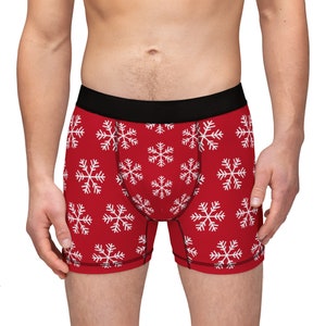 Puede incluir: Bóxers rojos con un patrón de copo de nieve blanco.
