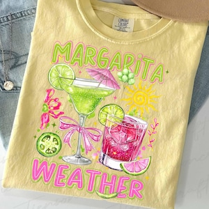 May include: Yellow t-shirt with a colorful graphic of two cocktails, a margarita and a pink drink, with lime slices and a sun. The words "Margarita Weather" are printed in green and pink.