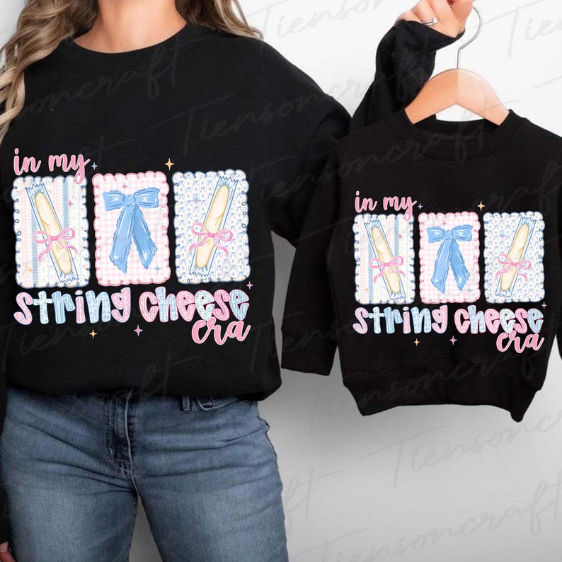 May include: Black sweatshirts with the text "in my...String cheese cra" in a whimsical font. The design features three illustrated rectangles with string cheese and bows. One sweatshirt is adult size, the other is child size.