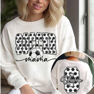 Pu&ograve; includere: Felpa color crema con le parole "SOCCER mama" in nero, con una grafica di pallone da calcio. La parola "SOCCER" &egrave; riempita con un motivo a pallone da calcio. Un inserto circolare mostra il retro della maglietta con il numero 8 e il nome "Olivia".
