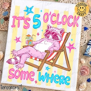 May include: White t-shirt featuring a cartoon raccoon in sunglasses, lounging in a deckchair with a cocktail. The text reads "IT'S 5 O'CLOCK SOMEWHERE" in pink and blue. The background has yellow and white stripes with star motifs.