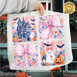 Puede incluir: Una lámina de tela blanca con un patrón repetitivo de cuatro ilustraciones distintas con temática de Halloween: una casa encantada azul, un gran lazo rosa a rayas con detalles florales, un segundo lazo rosa a rayas y un fantasma con una flor.