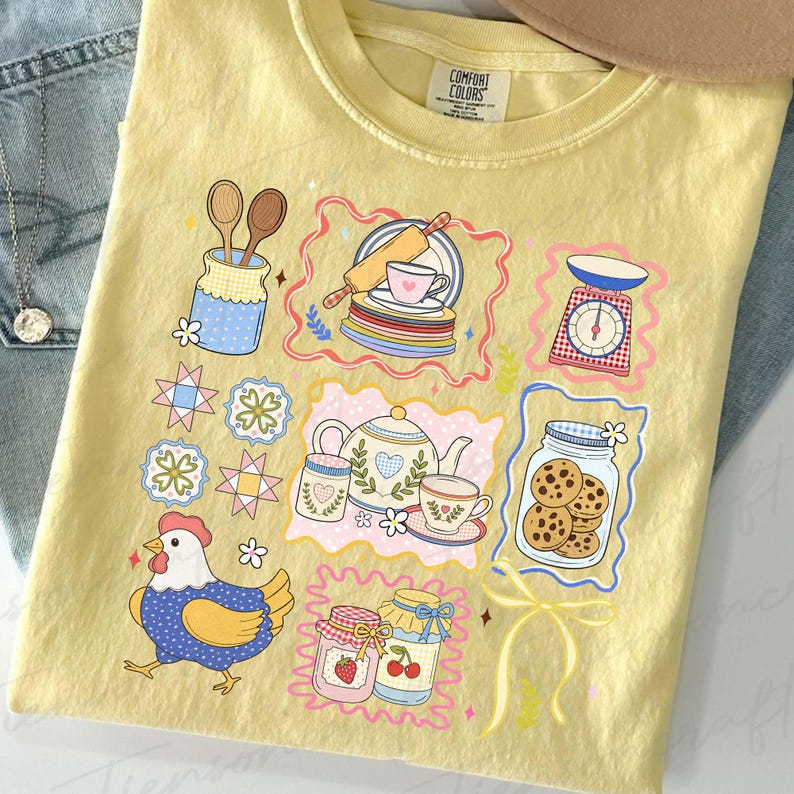 Puede incluir: Camiseta amarilla clara Comfort Colors con un gr&aacute;fico colorido con tem&aacute;tica de cocina. El dise&ntilde;o incluye una gallina, tarros, una tetera y utensilios para hornear. Un estilo casual y c&oacute;modo.